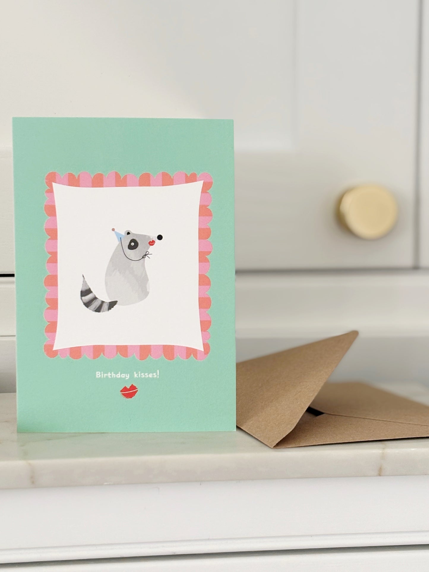 Racoon kisses birthday card with envelope