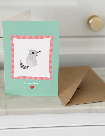 Racoon kisses birthday card with envelope